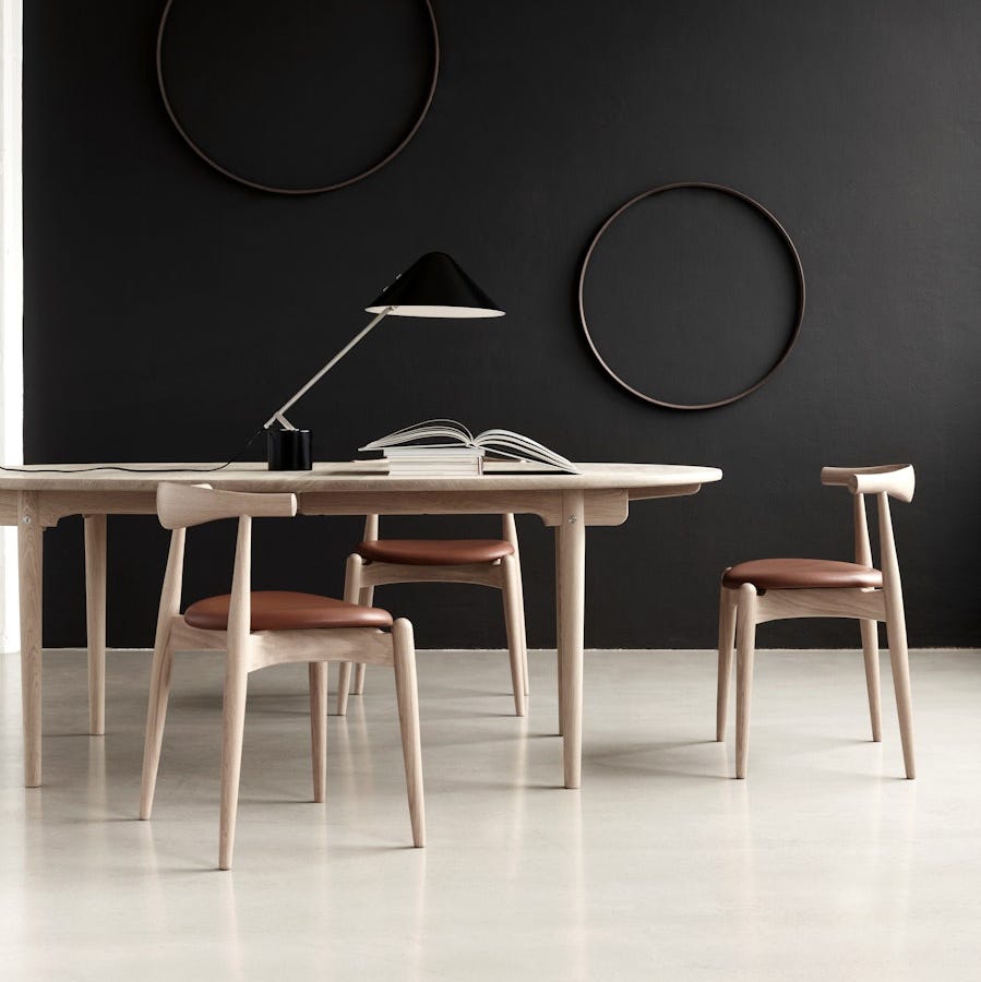 en moderne spisestue med et lyst trebord med to matchende stoler og en sort lampe