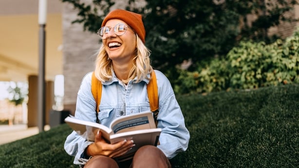 Ung munter hipsterkvinne som studerer utendørs på campus