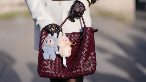   Gjesten har pÃ¥ seg en burgunder Bordeaux vevd Bottega Veneta Andiamo skinnveske, lyseblÃ¥ Labubu Bag Charm, Cream Labubu Bag Charm, utenfor Elie Saab, under Paris Fashion Week