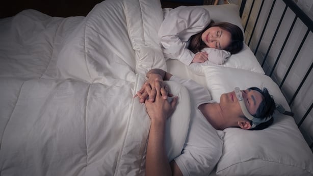 Par som sover i sengen med CPAP -maskin på sidebordet