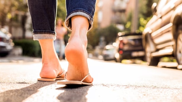 Kvinne iført flipflops som går nedover gaten på en solrik sommerdag- næring av føttene