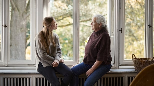 En bestemor og stordatter som sitter på et vinduskarmer og snakker