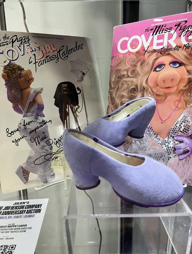 Den Miss Piggy-signerte Cover Girl fantasy-kalenderen 1981 og et par av hennes produksjonsslitte sko for sykkelscenen Couldn't We Ride fra The Great Muppet Caper vises under en forhÃ¥ndsvisning av jubileumsauksjonen til Jim Henson Company pÃ¥ Julien's Auctions lager i Gardena, California