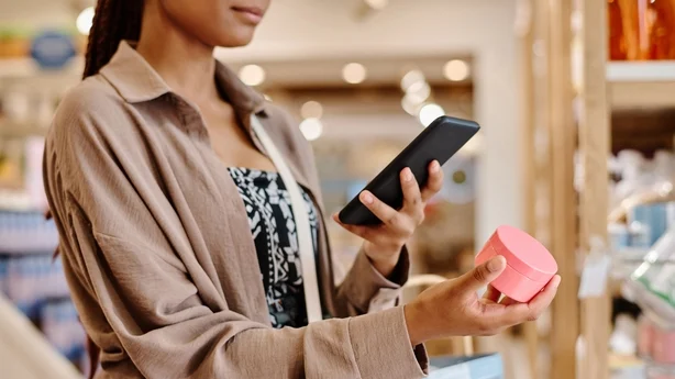 Nærbilde av ung kvinne som tar bilde av krem på smarttelefonen sin under shopping i butikken