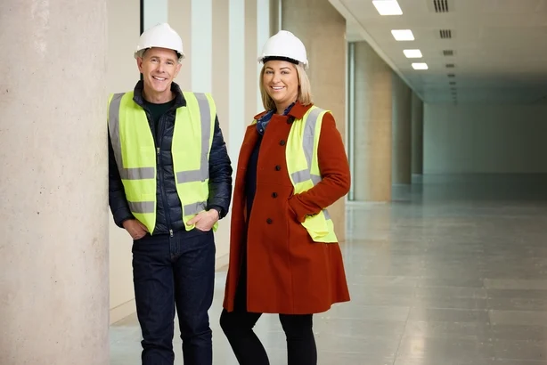 Dermot Bannon og Claire Irwin iført hi-vis vester og hjelmer