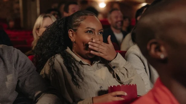 kvinne på kino, ler av en film