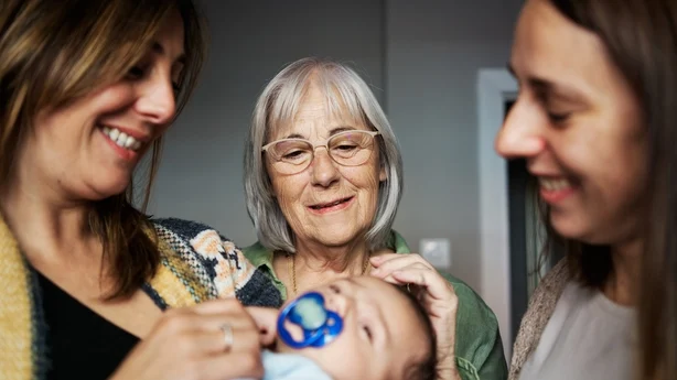 Bestemor ser på sitt nyfødte barnebarn i armen til moren sin