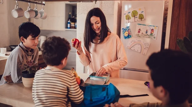 Mor tilbereder matbokser med sunn mat og snacks til sønner før hun går til skolen