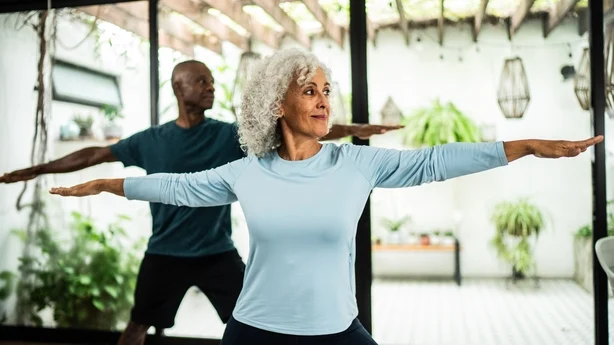 seniorpar som gjør yoga hjemme