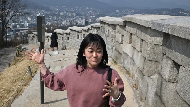 Emily Han snakker foran festningsmuren under et gateintervju med AFP i Naksan Park i Seoul 17. mars 2026. (Foto: Jung Yeon-je / AFP) / TO GO WITH AFP STORY