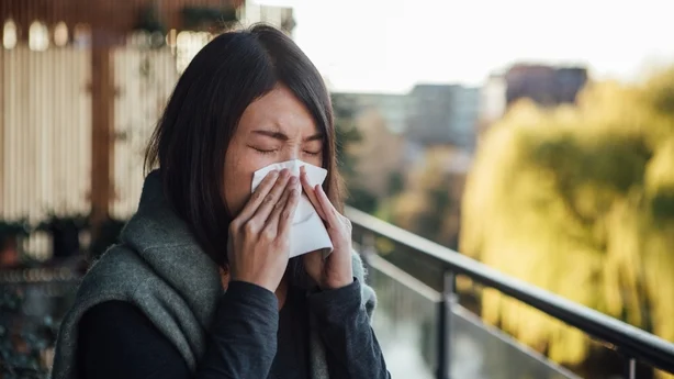 Hodeskudd av ung kvinne som har allergisymptomer, dekker nesen med vev mens hun nyser.