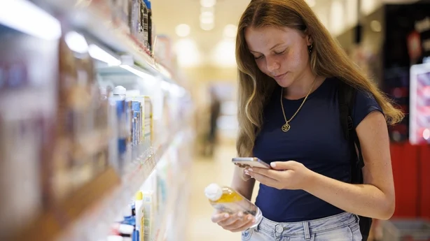 Tenåringsjente som sammenligner hudpleieprodukter i en butikk