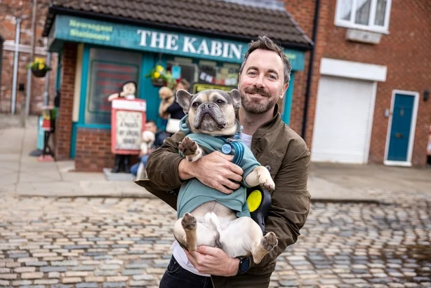 Brad Wood og Bobby, en fransk bulldog, pÃ¥ brosteinene i Coronation Street i Manchester. Foto: James Speakman/PA Media Assignments