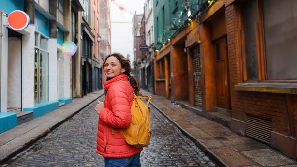 Glad kvinne som går i Dublins gamleby