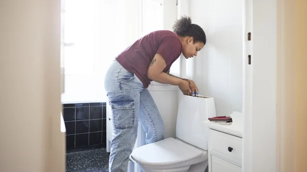 Midt voksen kvinne som reparerer sisterne på badet under oppussing av hjemmet