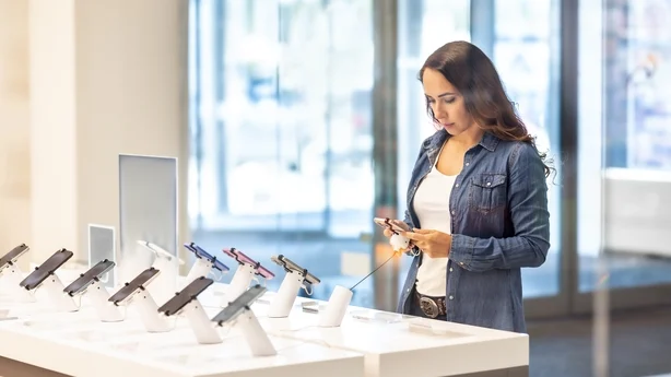 En pen brunette prøver ut en ny smarttelefon i en telefonoperatørs butikk. Hun blir kjent med den nye modellen.