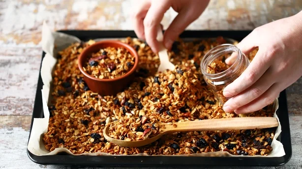 Nylaget hjemmelaget granola på en bakeplate. Granola i en tresleiv og i en krukke. Selektiv fokus. Sunt kosthold konsept. Keto diett.