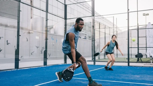 To positive venner som spiller padeltennis på takterrassen