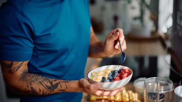 Nærbilde av mannen som spiser en sunn frokost på kjøkkenet.