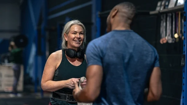 En personlig trener og en moden kvinne deler oppmuntring på et treningsstudio.