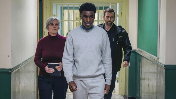 Marie Louise O'Dell (Siobhan Finneran) og Bailey (David Tennant) akkompagnerer Christopher Madubuko (Chukwubuikem Molokwu) i Time Foto: BBC/BBC Studios/Peter Marley