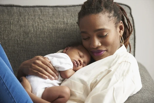Mor koser sovende babysønn på sofaen