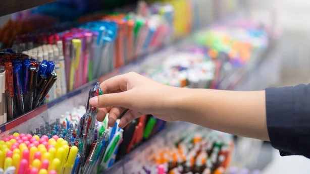 Nærbilde hender som velger skolepapir i supermarkedet.