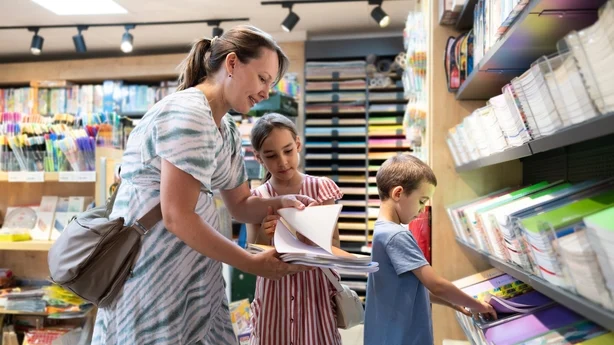 Tilbake til skolen shoppingkonsept. Mor og hennes to barn handler til skolen.