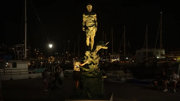 En gutt står ved siden av en statue av Odyssevs, skulpturert av Korina Cassianou, i byen Vathy på øya Ithaca. (Foto: Angelos Tzortzinis/AFP)