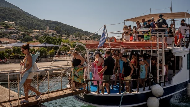 Turister går i land fra en båt etter å ha kommet tilbake fra nærliggende strender på øya Ithaca. (Foto: Angelos Tzortzinis/AFP)