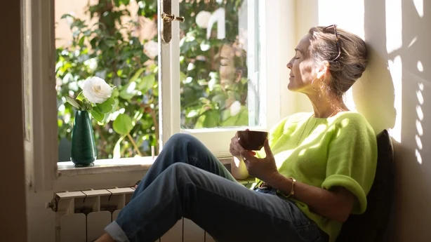 en eldre kvinne som sitter i et solfylt vindu