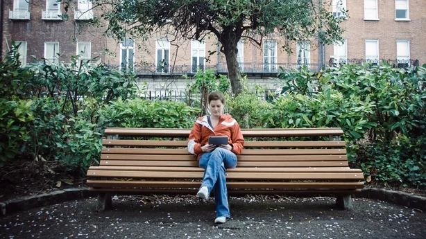 Ung kvinne nyter en dag i parken og leser fra sitt digitale nettbrett
