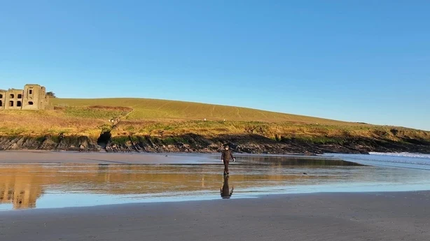 mann som står på en strand med et slott i bakgrunnen