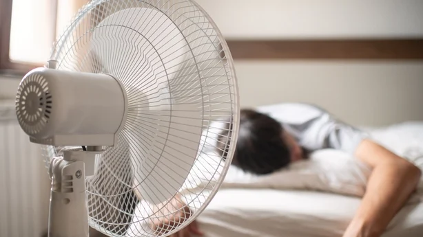 Mann som sover i nærheten av en elektrisk vifte