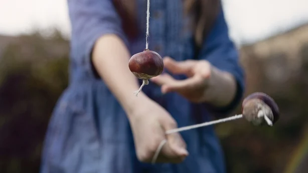 Jente som spiller tradisjonelle spill av conkers