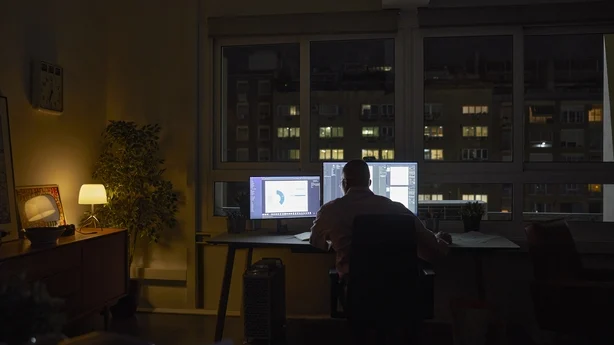 Silhouette mannlig profesjonell arbeider sent på kvelden på hjemmekontoret. 